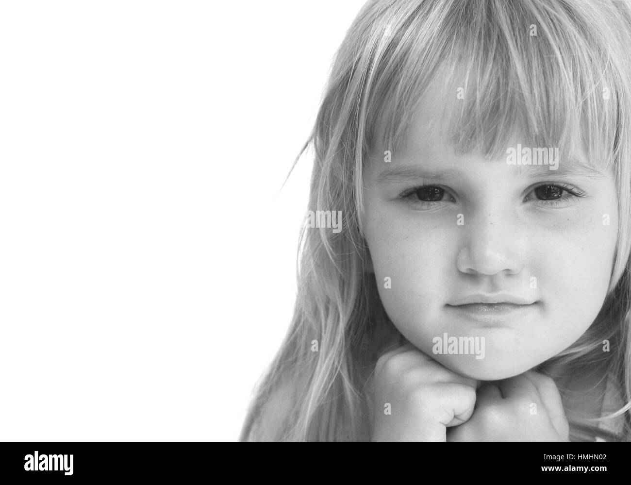 Ritratto di una bionda dai capelli bambina con una frangia e le mani sotto il suo mento contro uno sfondo bianco contemplando il pensiero serio staring Foto Stock