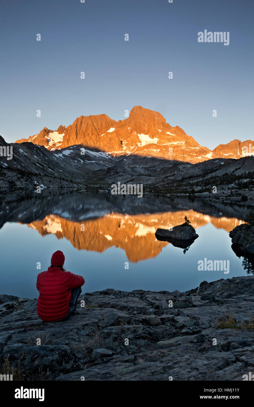 CA030143-00...CALIFORNIA - John Muir Trail escursionista osservare il tramonto sul Monte Ritter riflettente nel lago di granato in Ansel Adams Wilderness area. Foto Stock