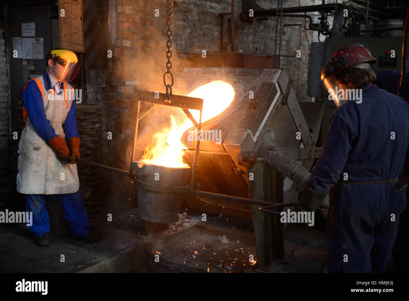 Foundrymen pour ferro fuso da un forno ad induzione in ladel presso una  piccola fonderia. (Shot in luce disponibile con profondità di campo Foto  stock - Alamy