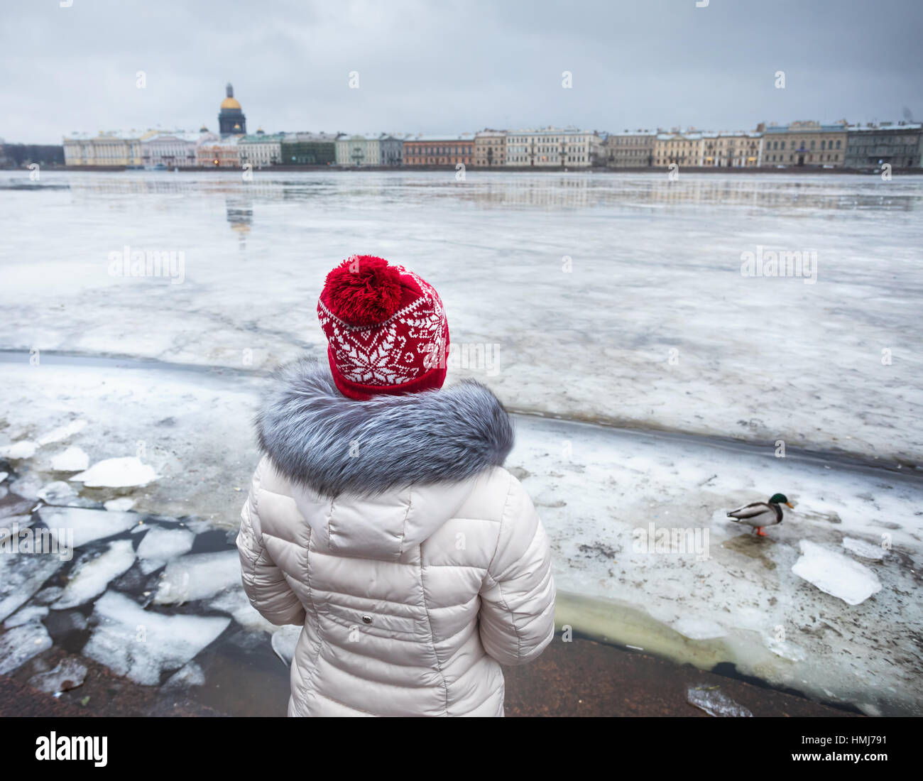 Woman in Red Hat vicino congelati fiume Neva con anatra e Isaac su altro lato in inverno a San Pietroburgo, Russia Foto Stock