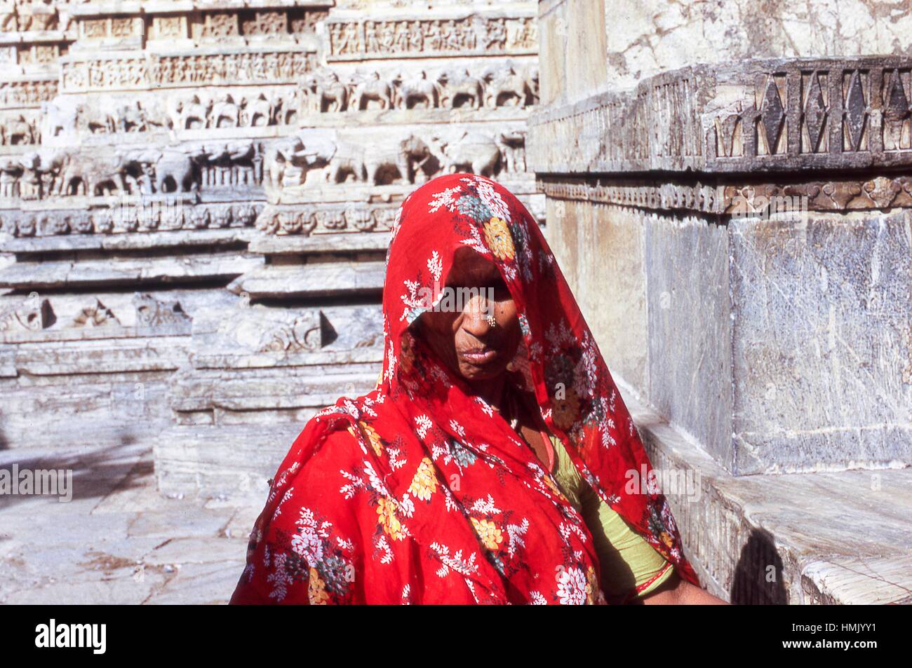 Ritratto di una donna mendicante con un argento nosering, in posa di fronte della parete le sculture presso il Tempio Jagdish, in Udaipur, Rajasthan in India nordoccidentale, novembre 1973. Foto Stock