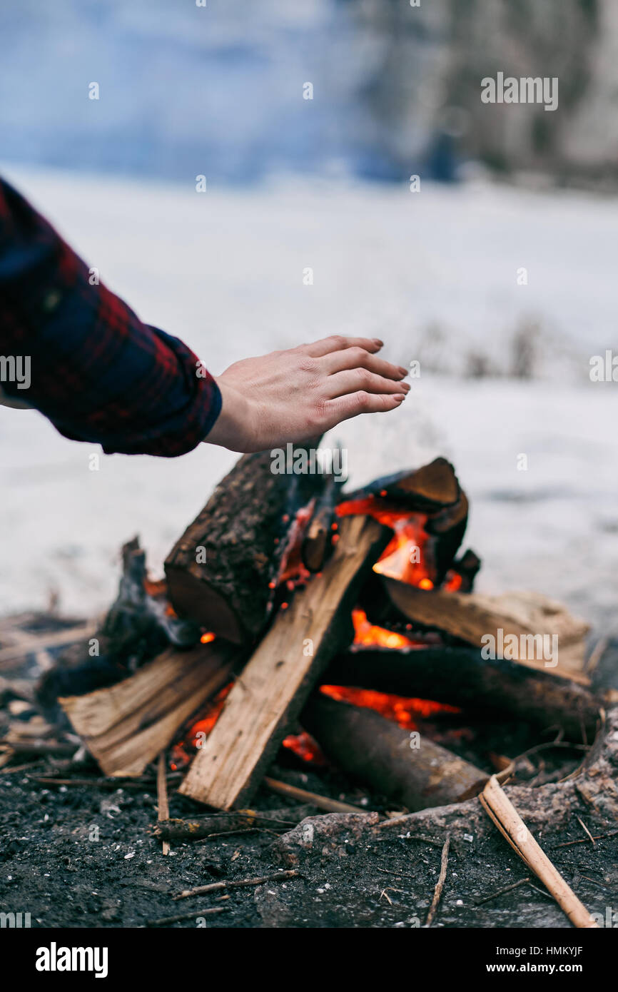 La ragazza si scalda le mani in prossimità di un fuoco in inverno Foto Stock