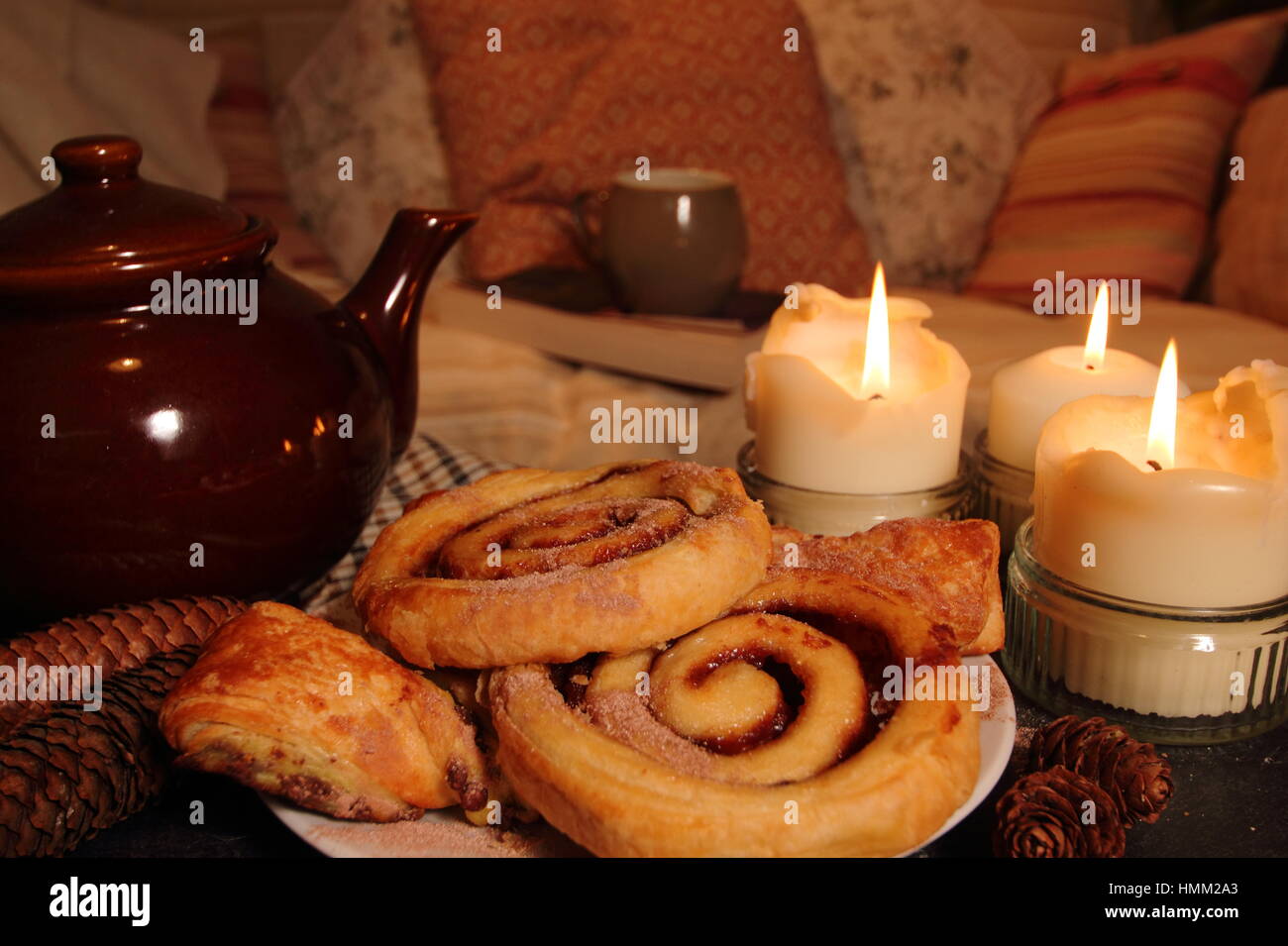 Accogliente candela accesa soggiorno con pasticcini, tè, un tiro e un buon libro in un inglese home ispirato Hygge; danese un concetto di semplice felicità Foto Stock