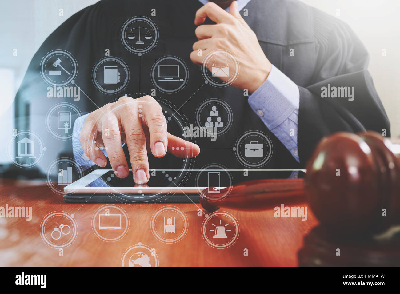 La giustizia e la nozione di diritto.Giudice maschi nelle aule di un tribunale con il martello,lavora con tavoletta digitale del computer sul tavolo di legno,virtual interface grafica icone di Foto Stock