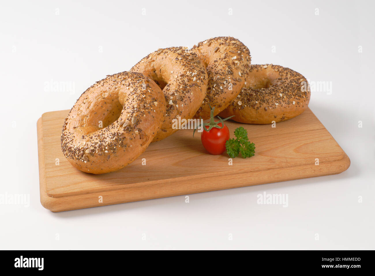 Bagel freschi e rabboccato con semi sul tagliere di legno Foto Stock