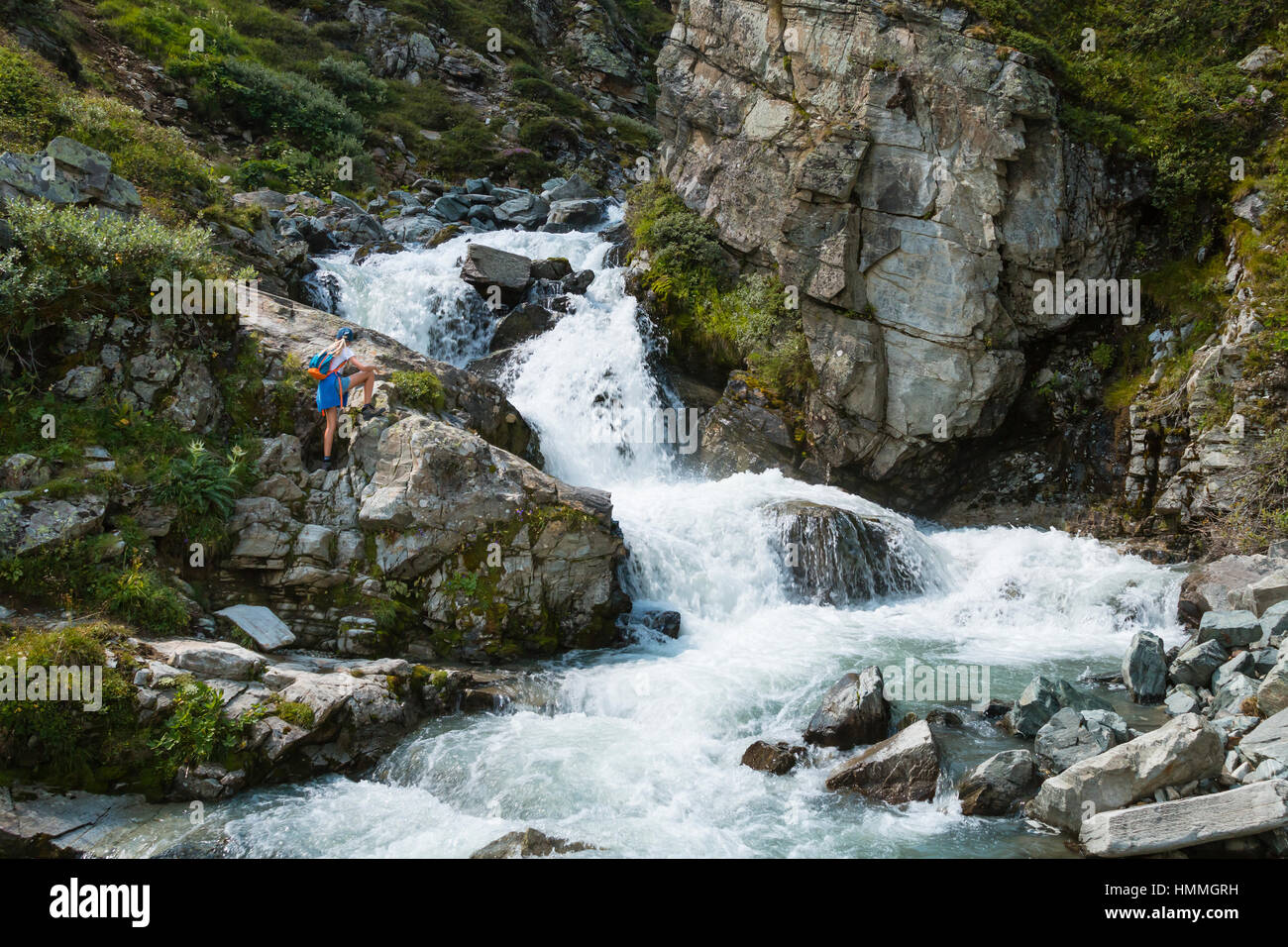 SILVRETTA - 13 agosto: una giovane donna in abiti da escursionismo la visione di una cascata di montagna nella regione di Silvretta, Austriay il 13 agosto 2015. Foto Stock