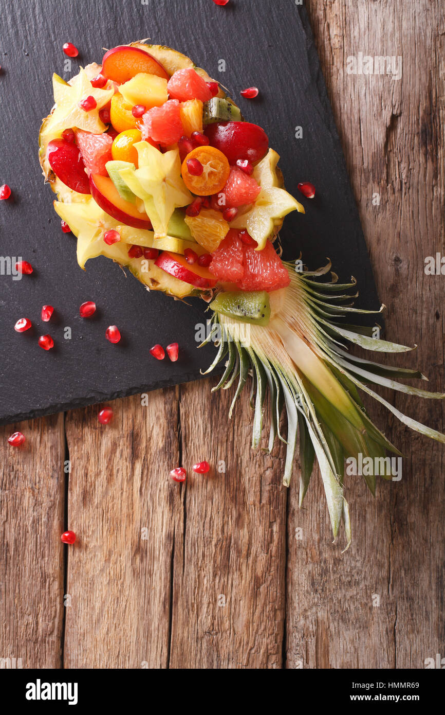 Ananas ripieni con freschi frutti esotici vicino sul tavolo. vista verticale da sopra Foto Stock