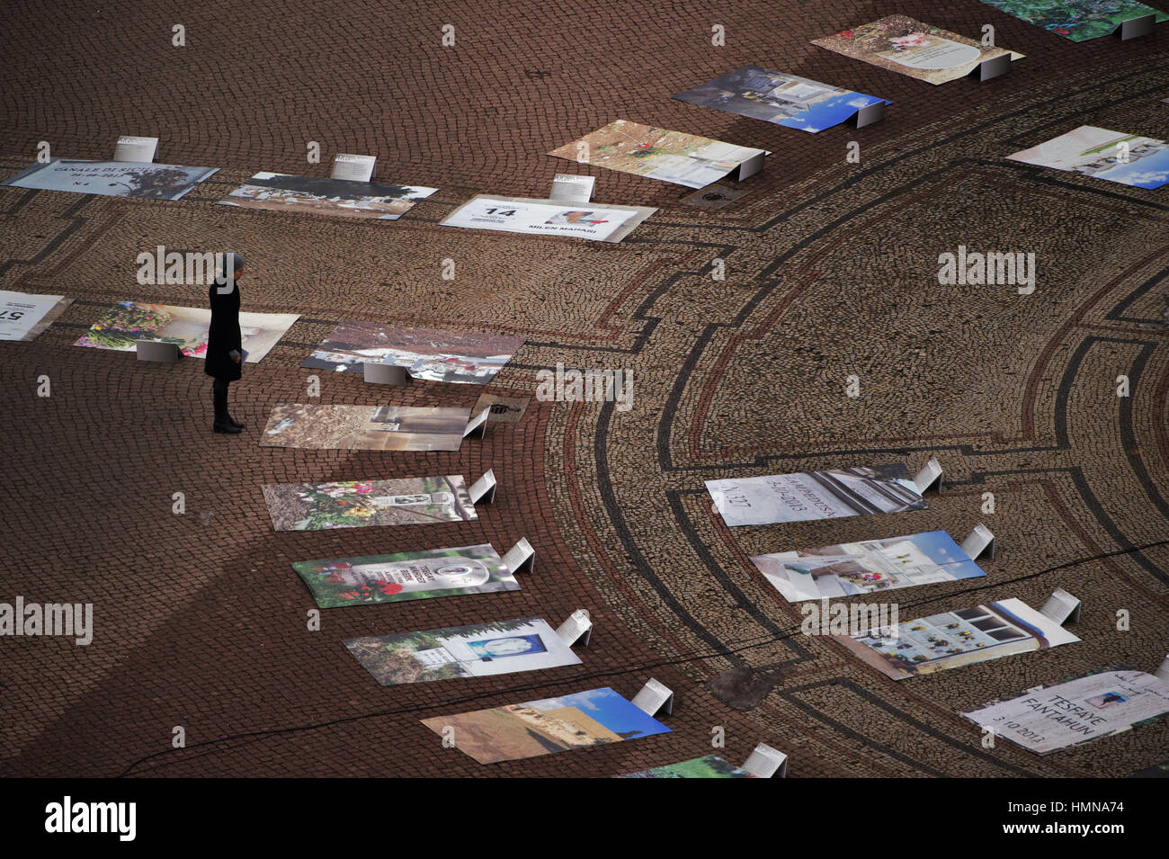 Dresden, Germania. 10 Febbraio, 2017. Una donna guarda fotografie di grandi dimensioni disposti in Piazza del Teatro di Dresda, in Germania, il 10 febbraio 2017. Novanta fotografie delle tombe dei rifugiati che sono annegati nel Mediterraneo in Sicilia, l'Italia, sono sul display come parte della città in corso di esame del modo in cui la distruzione della città durante la Seconda Guerra Mondiale è ricordato. Foto: Arno Burgi/dpa-Zentralbild/dpa/Alamy Live News Foto Stock