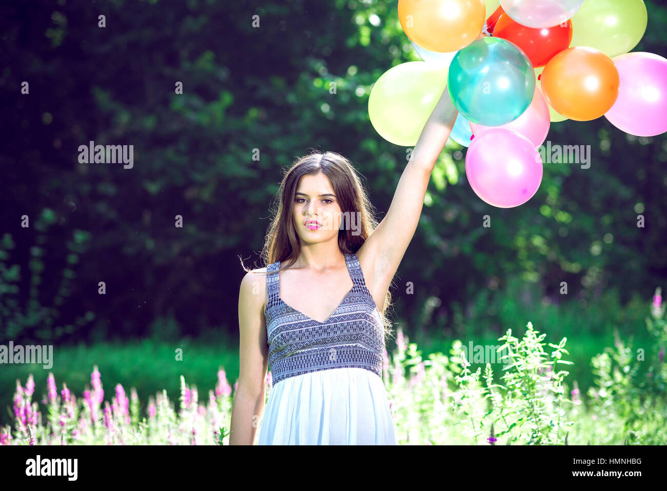 Ragazza in natura azienda palloncini indossando abito bianco Foto Stock