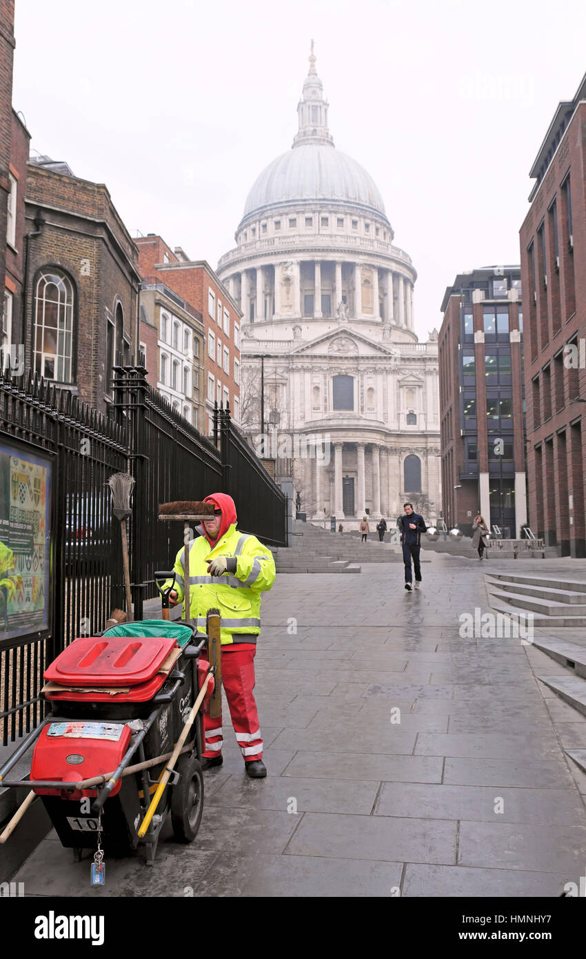 Pulitore di via con dustcart in abbigliamento invernale lavora vicino alla Cattedrale di St Paul nella City di Londra, UK KATHY DEWITT Foto Stock