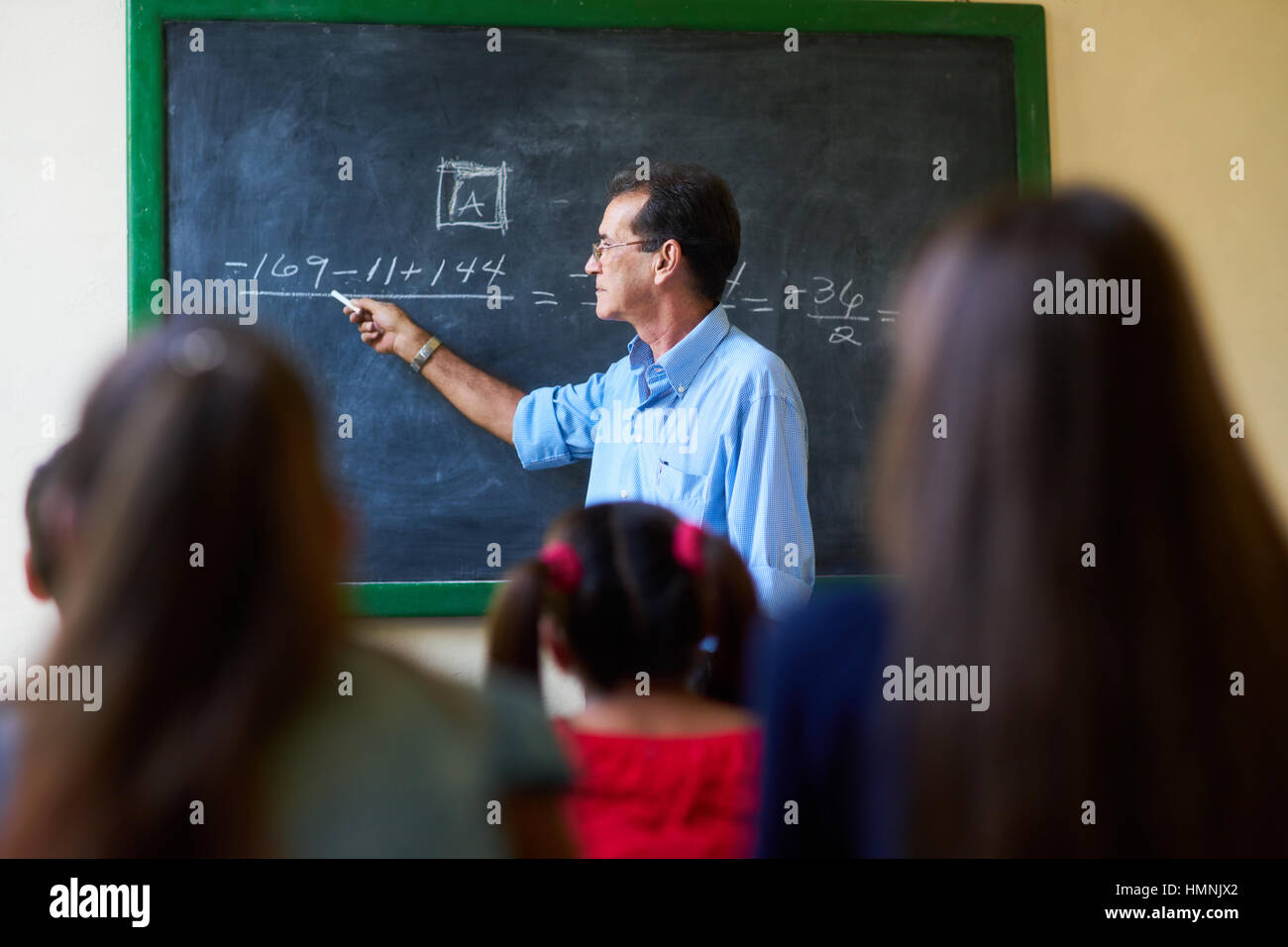 I giovani e l'istruzione. Gruppo di studenti ispanici in classe a scuola durante la lezione. Focus su insegnante alla lavagna per spiegare la matematica. Foto Stock