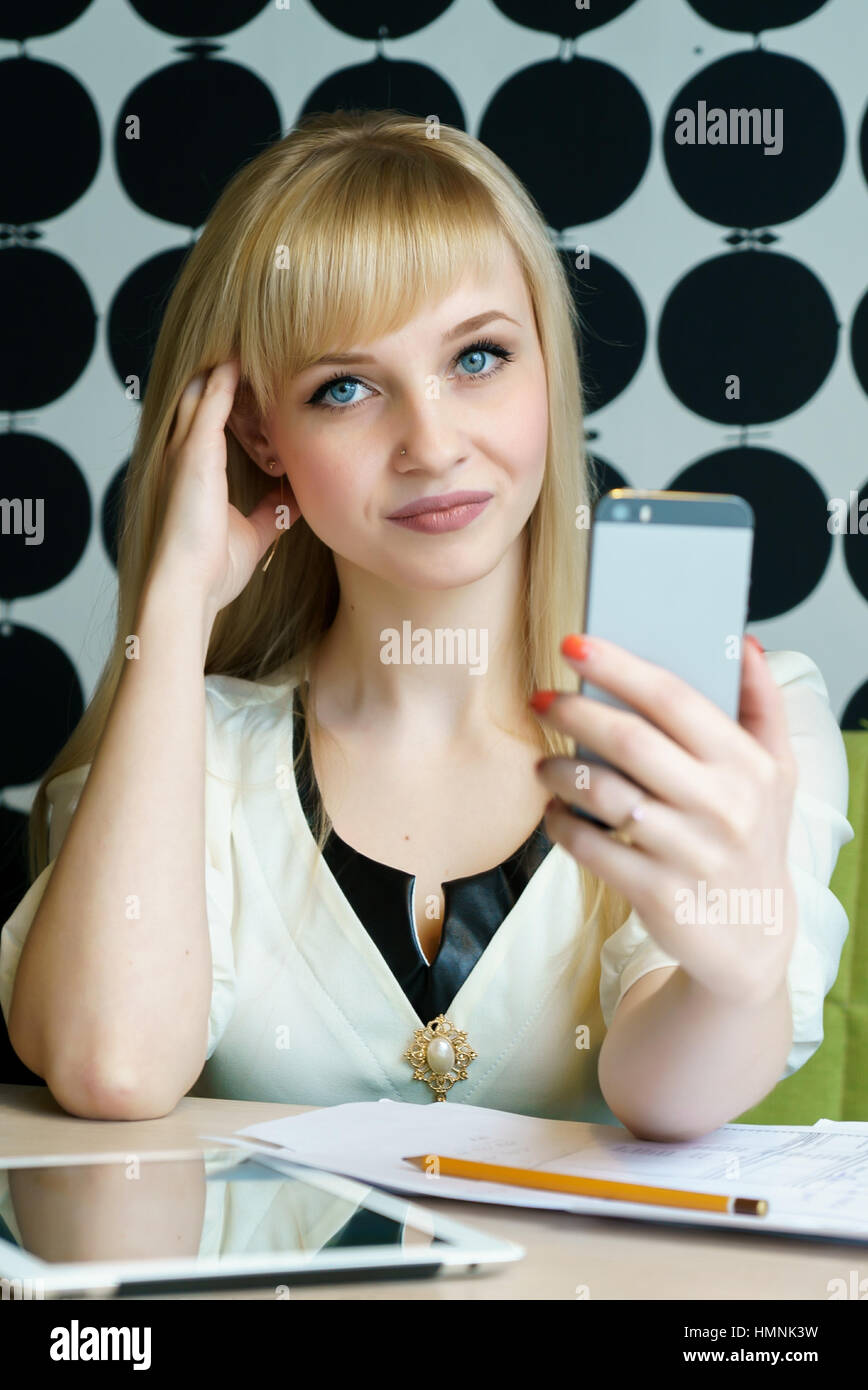 Ragazza seduta in cafe contiene uno smartphone Foto Stock