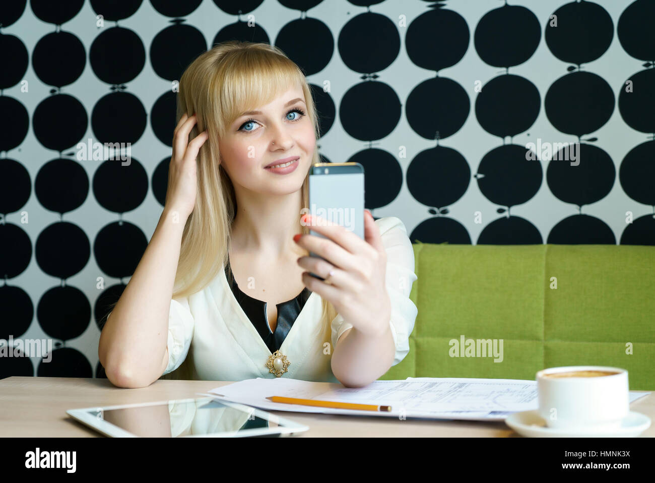 Ragazza seduta in cafe possiede un telefono cellulare Foto Stock