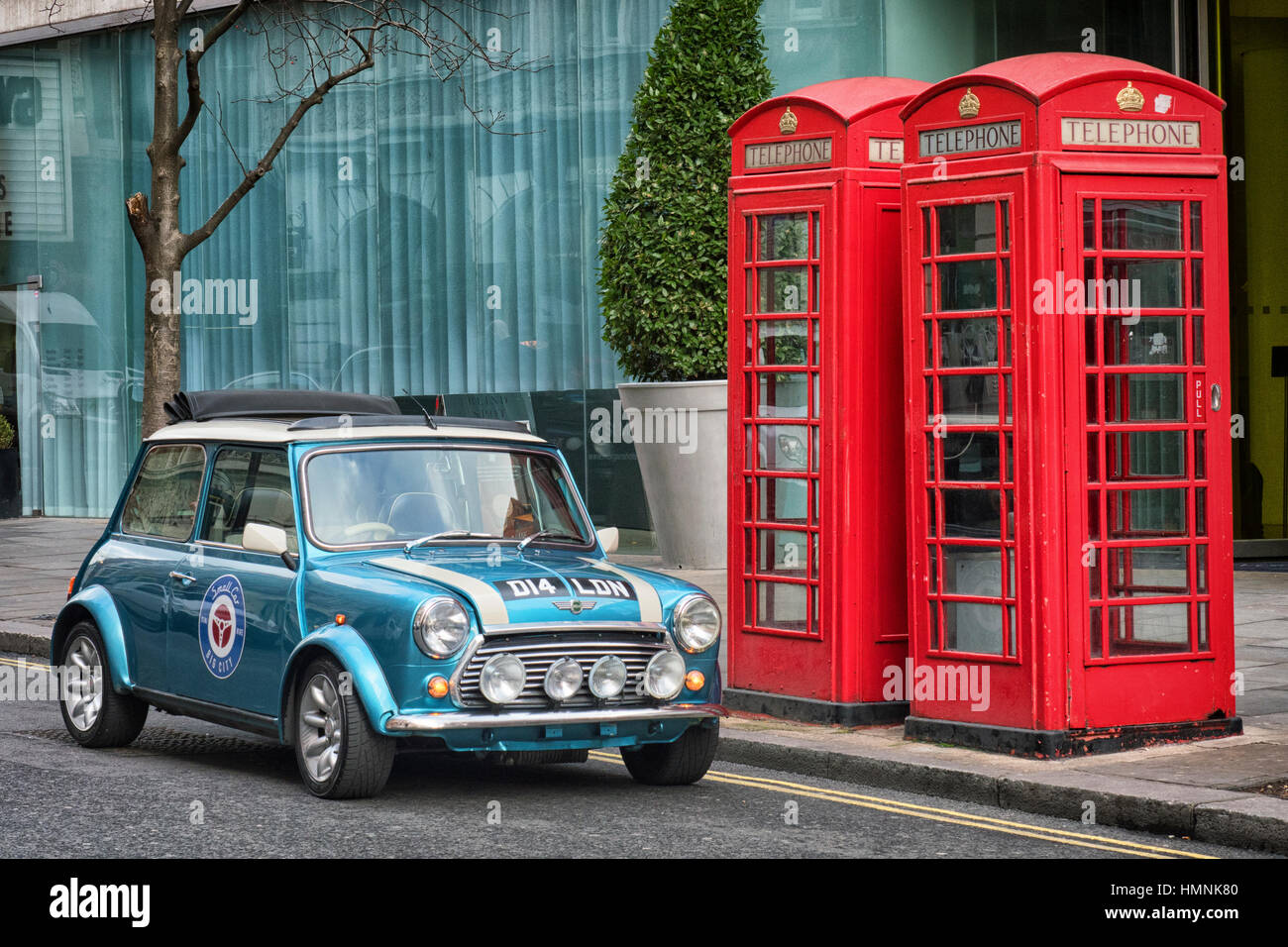 Austin Mini Cooper parcheggiata accanto alle cabine telefoniche rosse in St Martin's Lane nel centro di Londra Foto Stock
