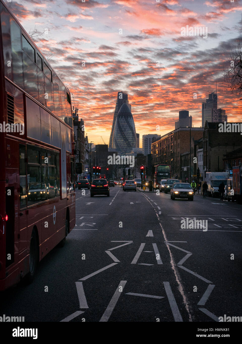 Whitechapel Road nella East End di Londra al tramonto guardando verso il miglio quadrato della città di Londra con 30 St Mary Axe noto come il Gherkin Foto Stock