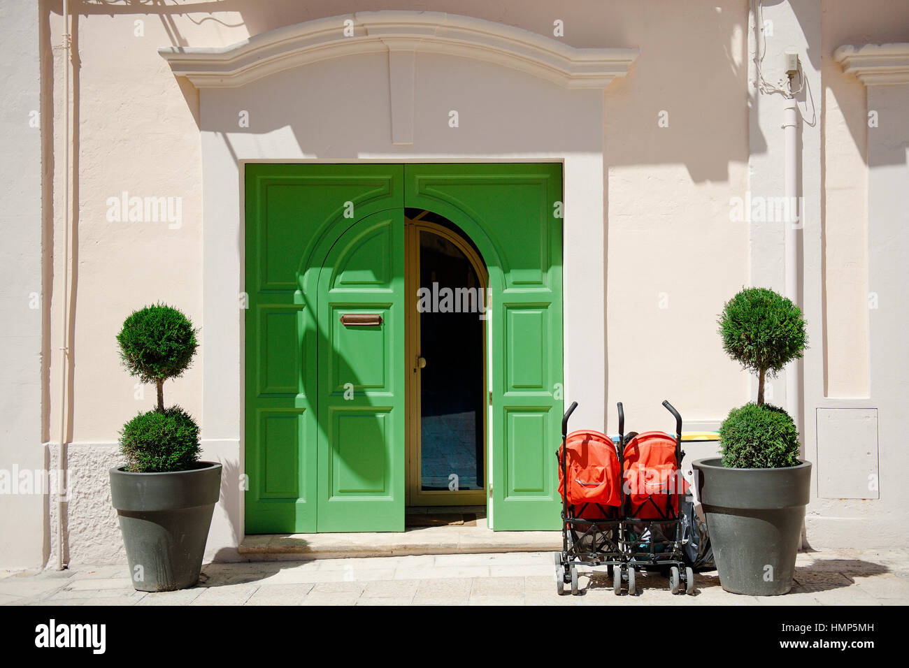 Sportello Verde, due piccole piante e red passeggino Foto Stock