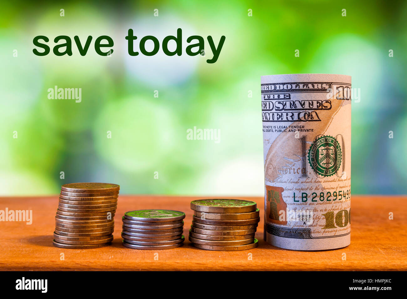 Un centinaio di dollaro statunitense Bill laminati banconota con monete in centesimi di dollaro americano sul verde sfumato bokeh sfondo. Salvare il concetto di oggi Foto Stock