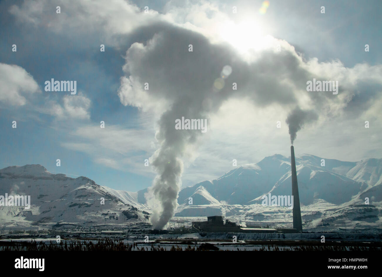 Produca Il fumo al di fuori di un fumaiolo e il foro da una fusione di rame pianta con una montagna dietro di esso nello Utah. Foto Stock