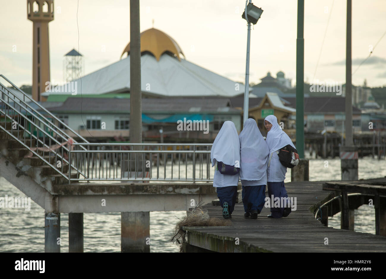 Tre ragazze musulmane sono sulla loro strada a casa dalla scuola di istruzione che attraversa l'acqua utilizzando la passerella nel Water Village Settlement (Kampong Ayer) a Bandar seri Begawan, Brunei. © Time-Snap Foto Stock