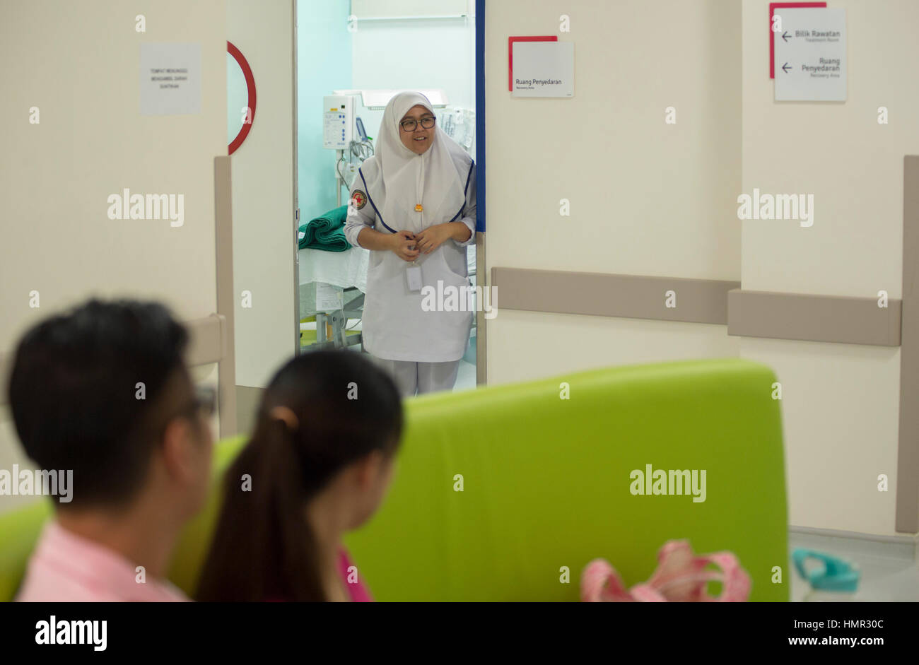 Un'infermiera è in piedi nel telaio della porta come sta chiamando il paziente seguente all'ospedale femminile & del bambino del Raja Isteri Pengiran Anak Saleha Hospital (RIPAS) a Darussalam, Brunei. © Time-Snap Foto Stock