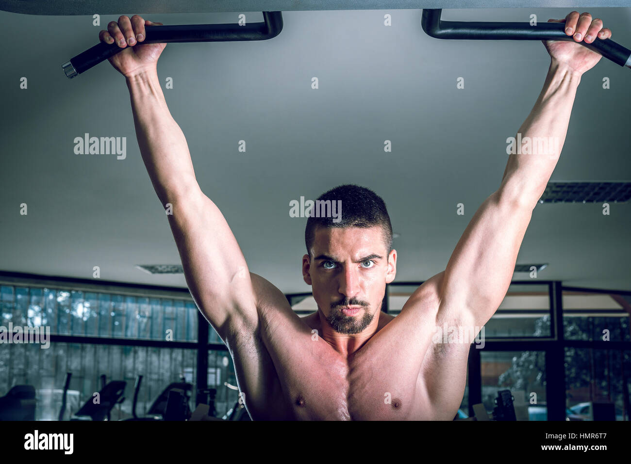 Giovane uomo adulto facendo tirare verso l'alto esercizio in palestra. Foto Stock