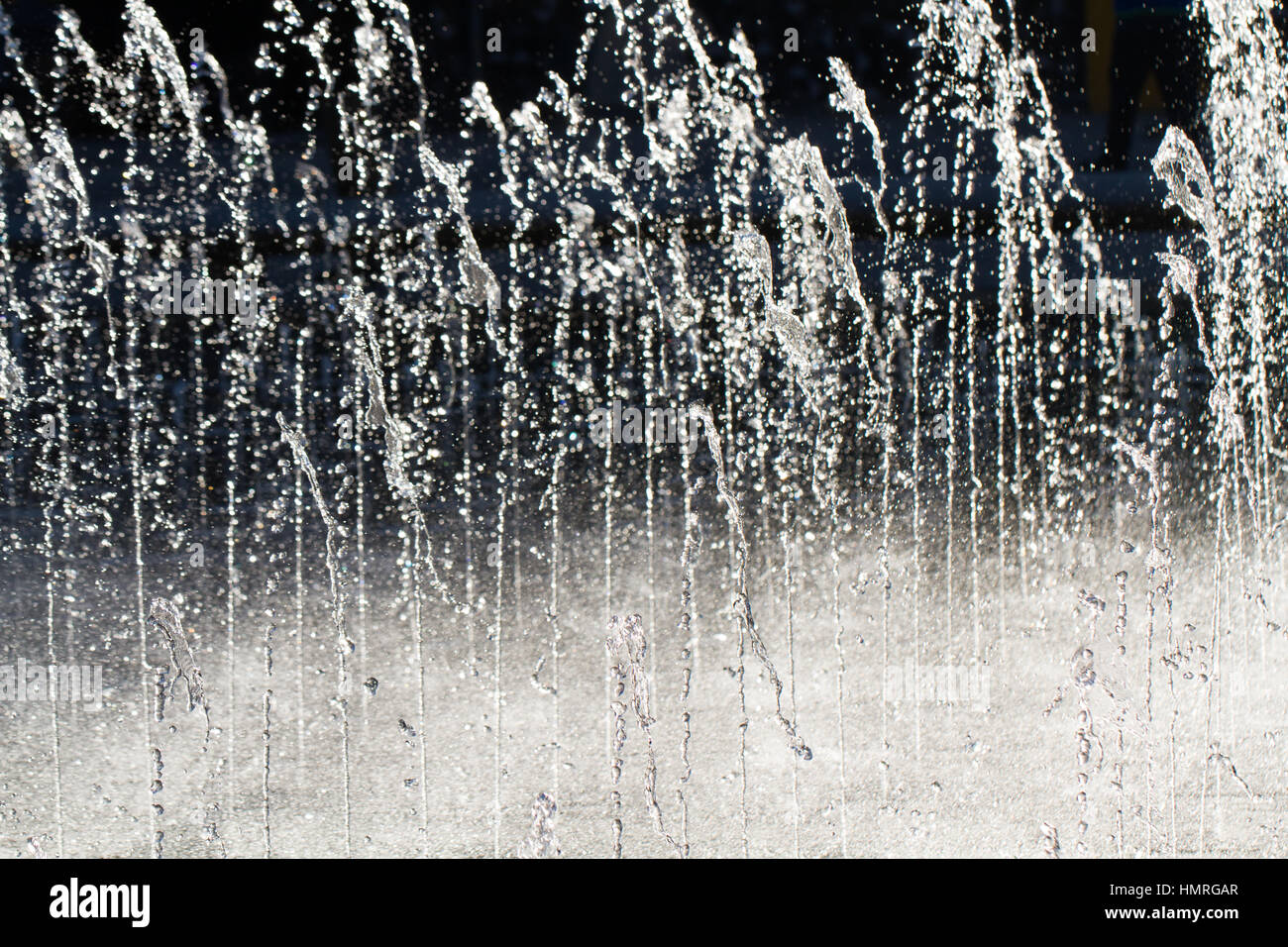 Getti di freddo, acqua chiara uscito verso l'alto e schizzi sul terreno in un contrasto elevato, full frame di immagine di sfondo. Foto Stock