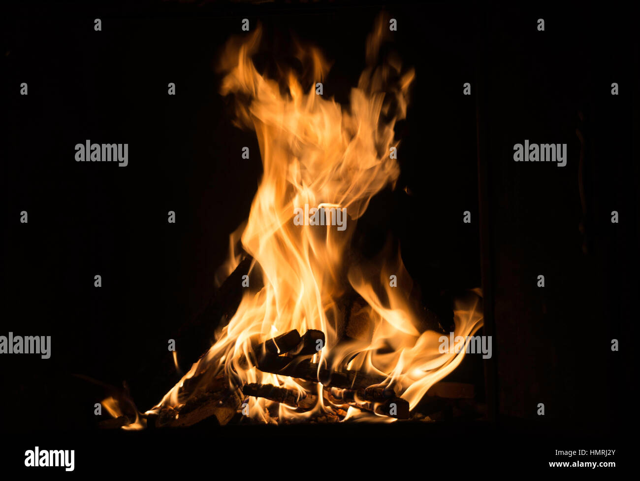 Brillante arancio fuoco e sfolgorante su firelogs, sfondo nero Foto Stock