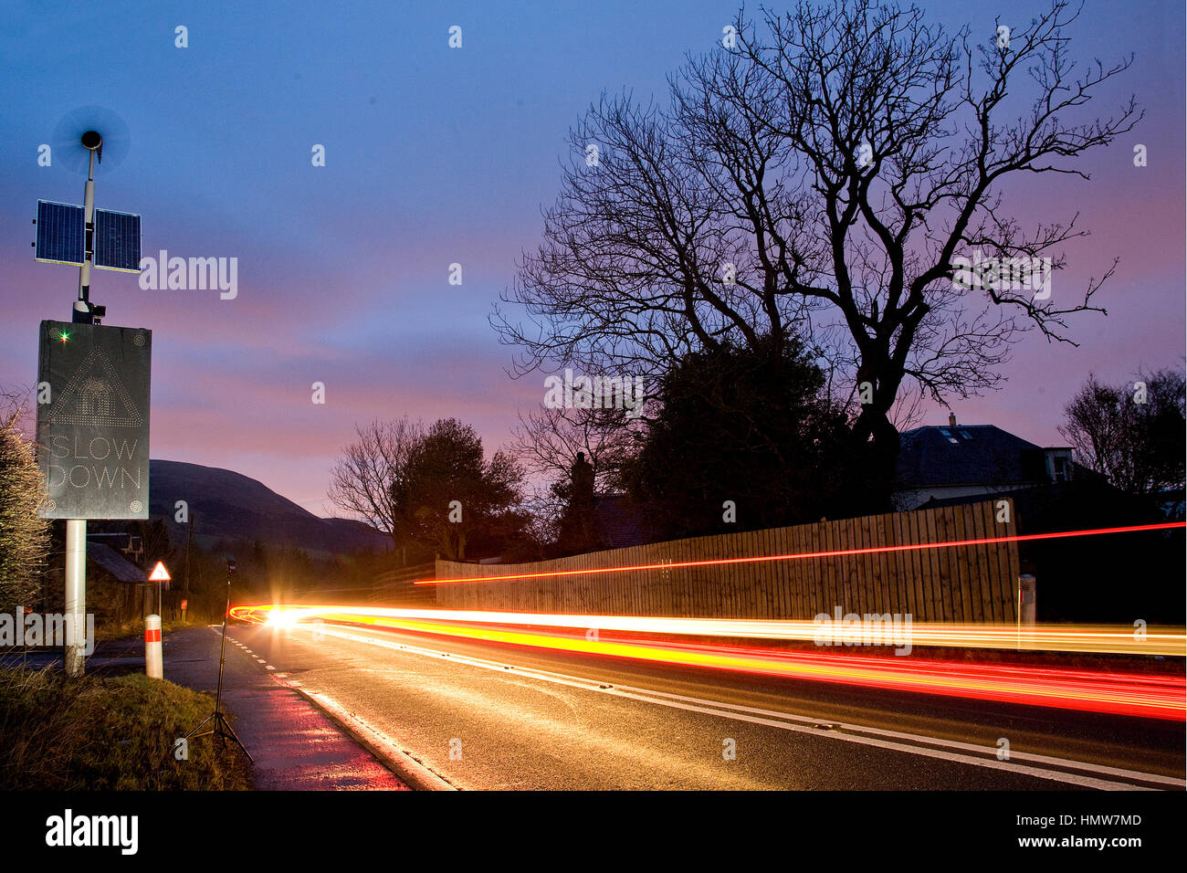 Energia solare ed eolica powered cartello stradale sulla strada che conduce a Edimburgo in Scozia, Regno Unito durante la notte con le automobili che passano. Foto Stock