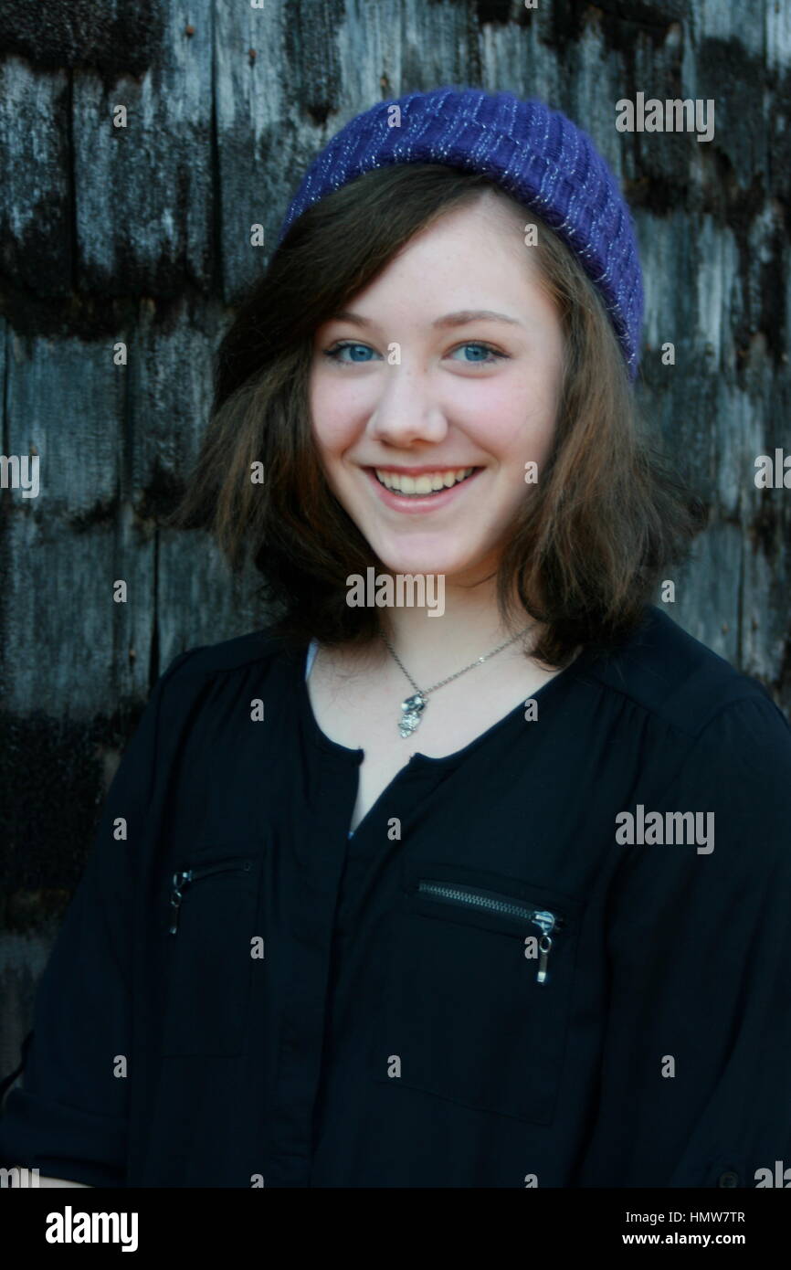 Capelli marrone, blu eyed teen in viola calza hat in piedi accanto alla parete incastrata. Foto Stock