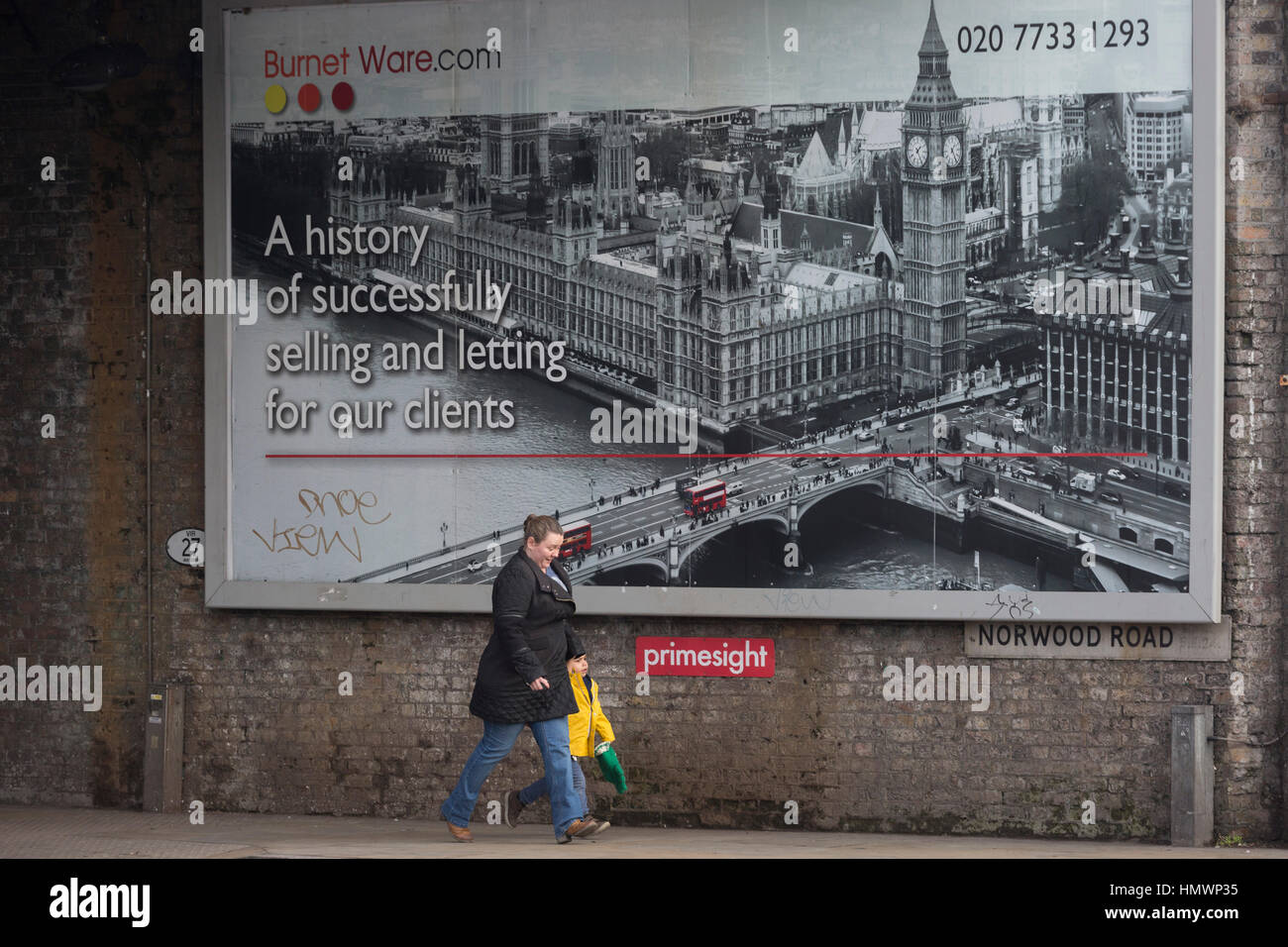 Un londinese passeggiate al di sotto di una pubblicità tramite Affissioni l'agente immobiliare Burnett Ware, il 6 febbraio 2017, a Herne Hill, London borough di Lambeth, Inghilterra. Foto Stock