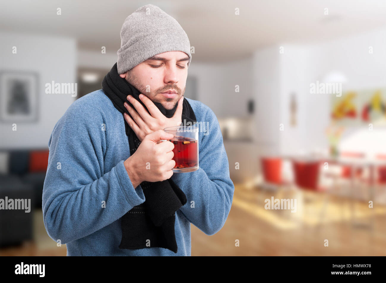 Giovane uomo malato bere il tè caldo per trattare la sua influenza all'interno della casa con spazio di copia Foto Stock