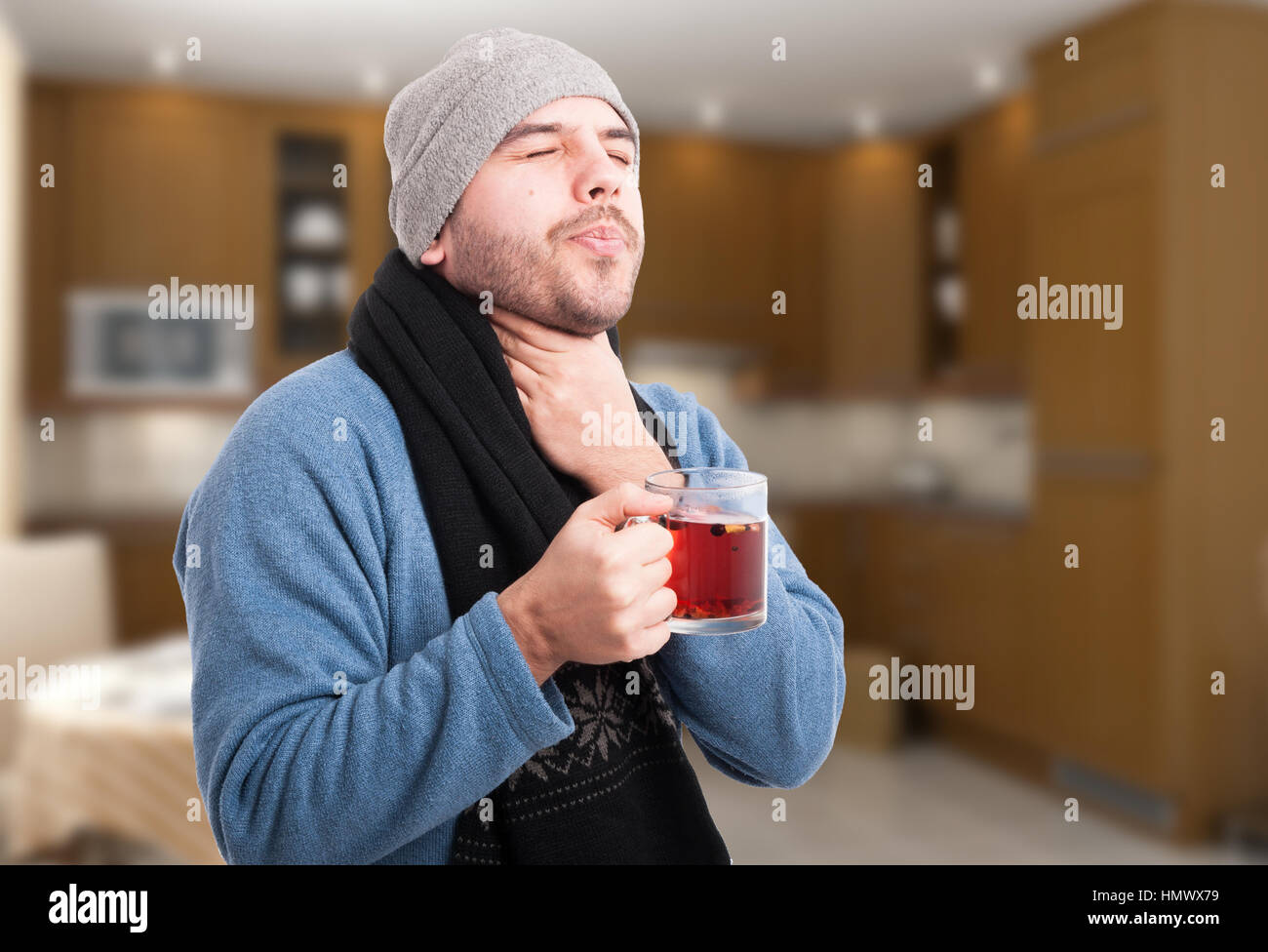 Bel uomo avente un mal di gola e di bere il tè caldo a casa sua Foto Stock