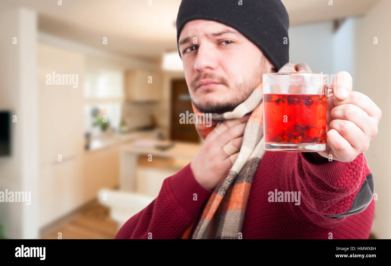 Uomo bello con gola irritata tenendo una tazza di tè caldo con copia spazio di testo Foto Stock