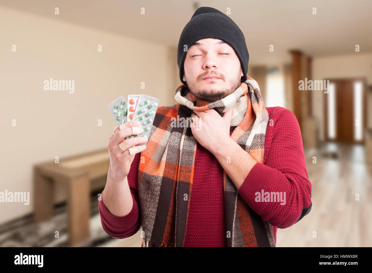 Giovane uomo con gola infiammata holding blister con le pillole in mano Foto Stock