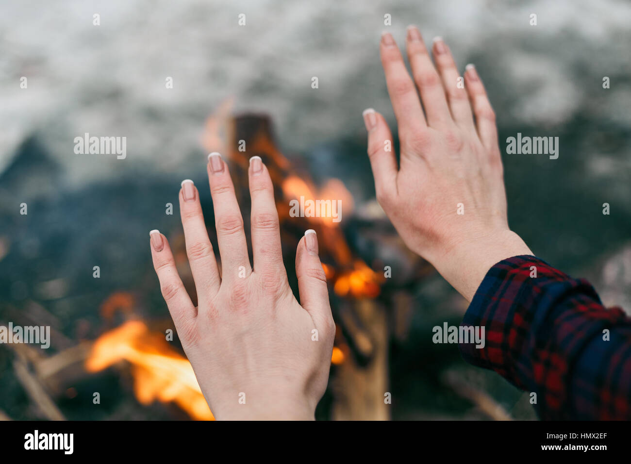 La ragazza si scalda le mani in prossimità di un fuoco in inverno Foto Stock