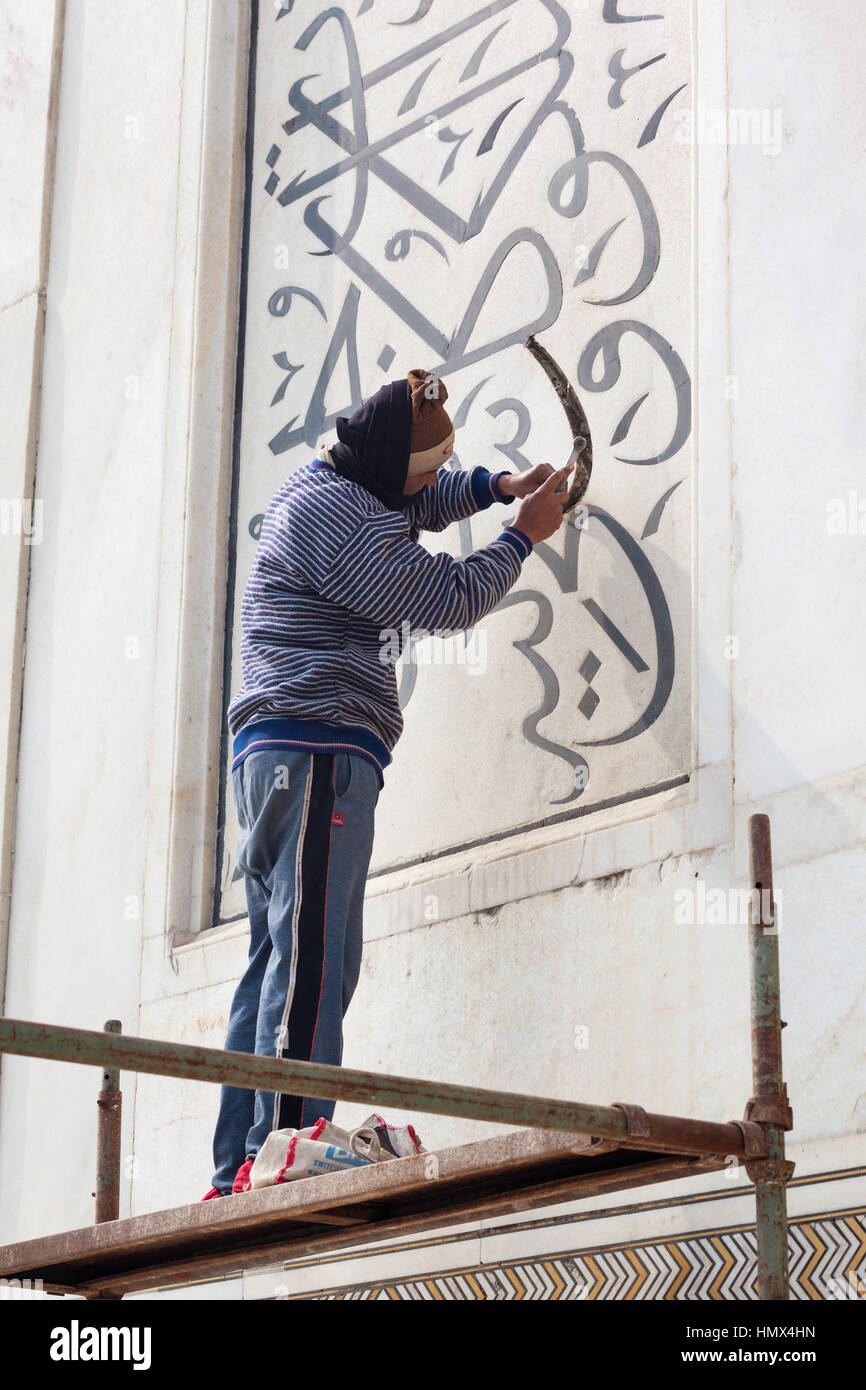 AGRA, India - 13 gennaio 2015 : un artigiano su una impalcatura riparazione calligrafica iscrizioni in marmo del nord est minareto al Taj Maha Foto Stock