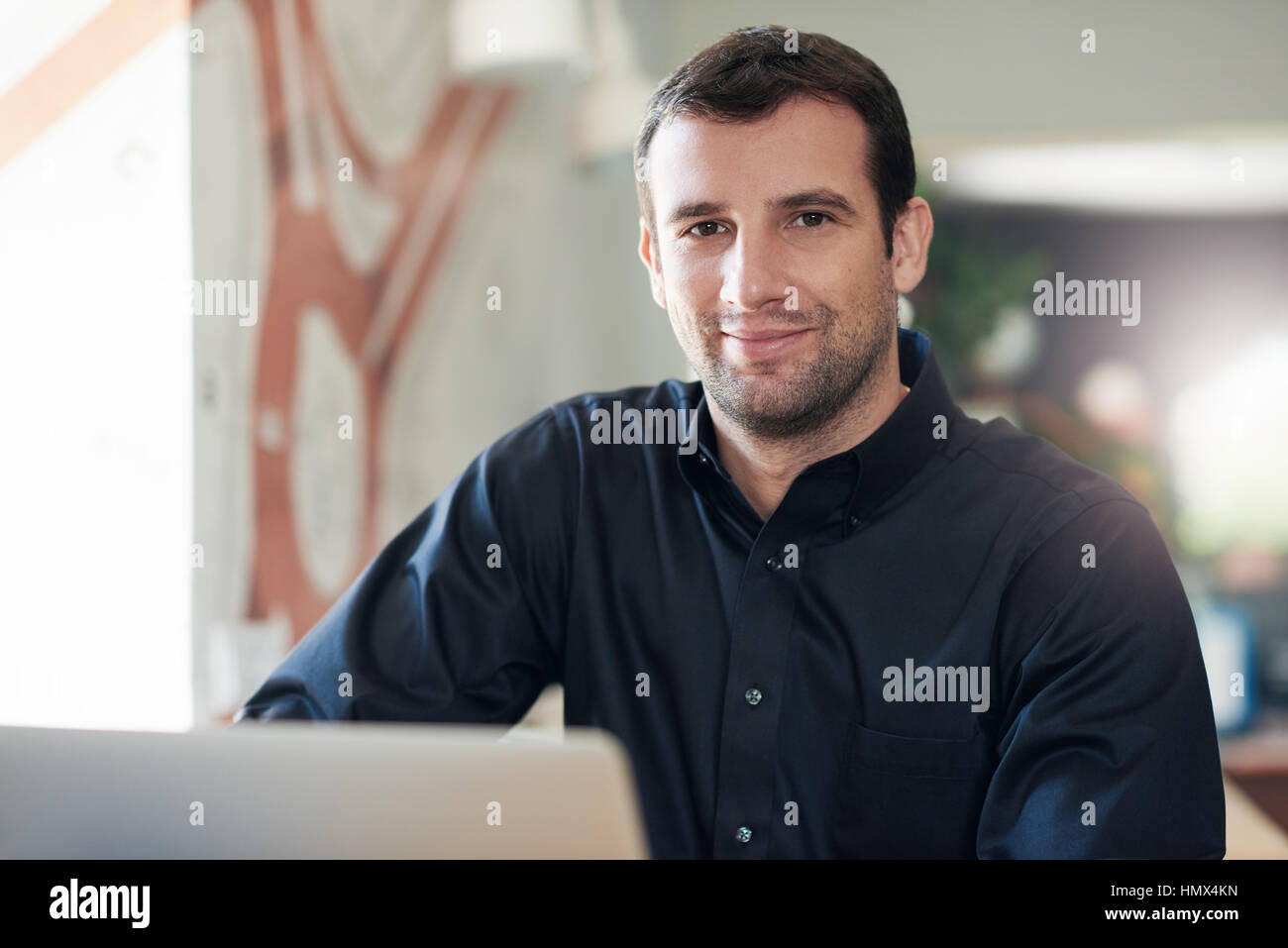 Imprenditore di successo sorridente e utilizzando un computer portatile in un ufficio Foto Stock
