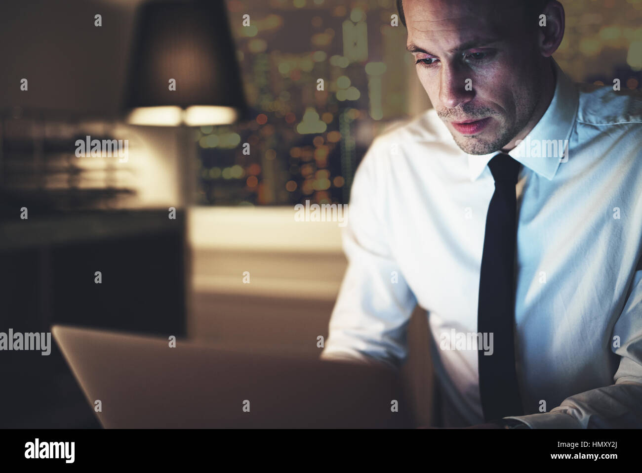 Imprenditore serio lavoro su laptop in seduta notturna in Office cerca concentrata Foto Stock