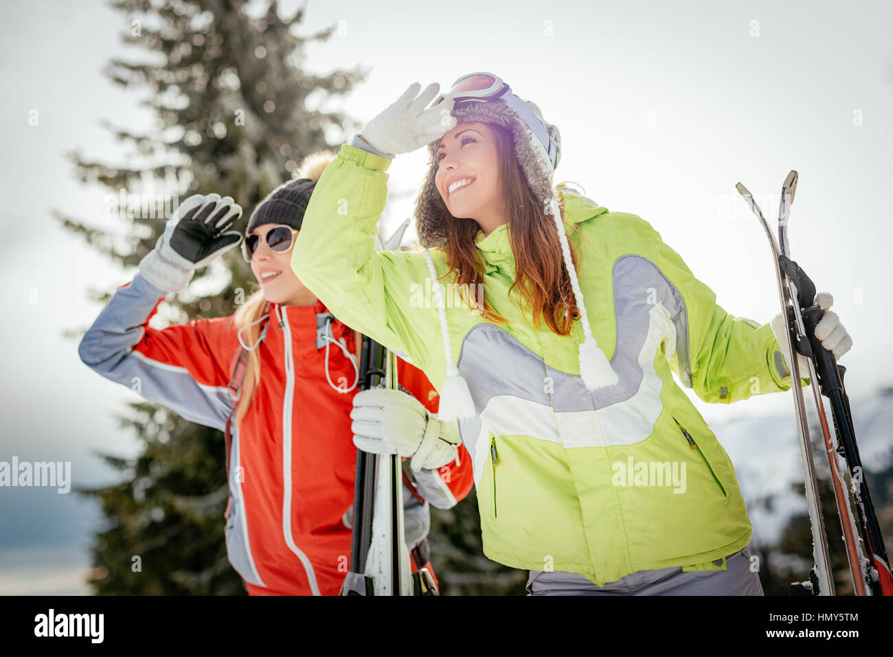 Bella giovane donna amici godendo di una vacanza invernale. Essi in piedi con gli sci e guardando lontano con il sorriso. Foto Stock