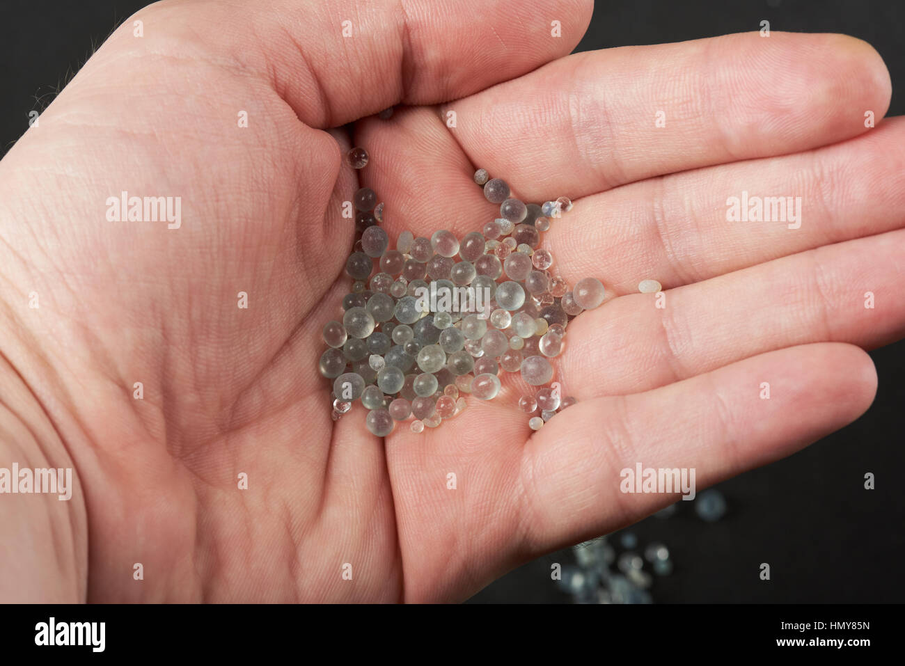 Stretta di mano che tiene in granuli di gel di silice Foto Stock