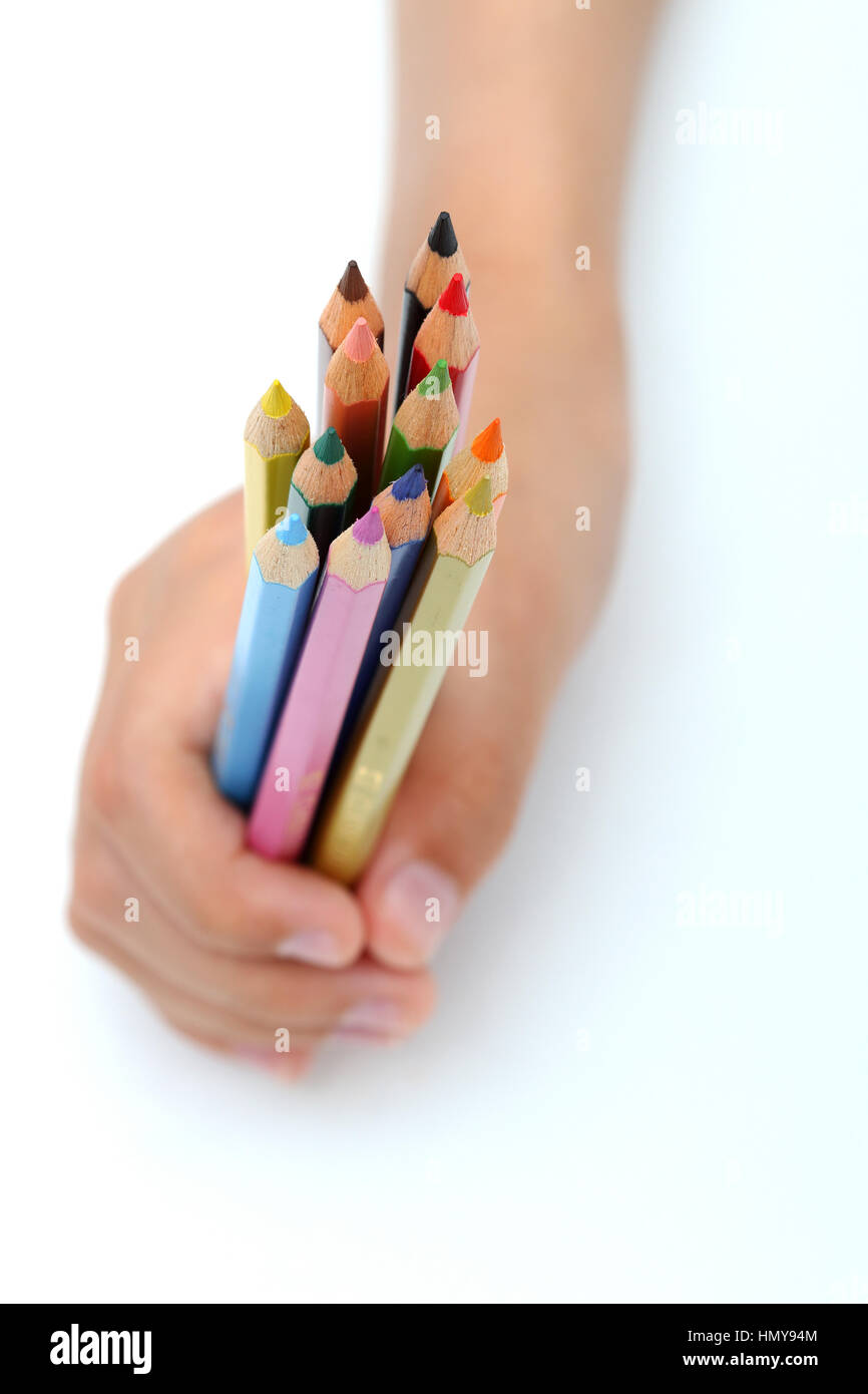 Stretta di mano destra presa matite di colore isolata contro uno sfondo bianco Foto Stock