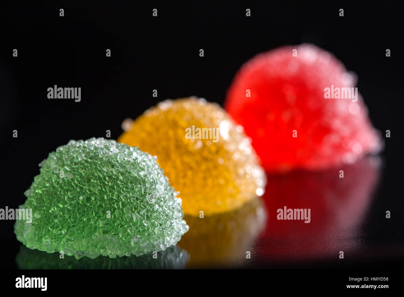 Tre jelly caramelle su sfondo scuro con la riflessione Foto Stock