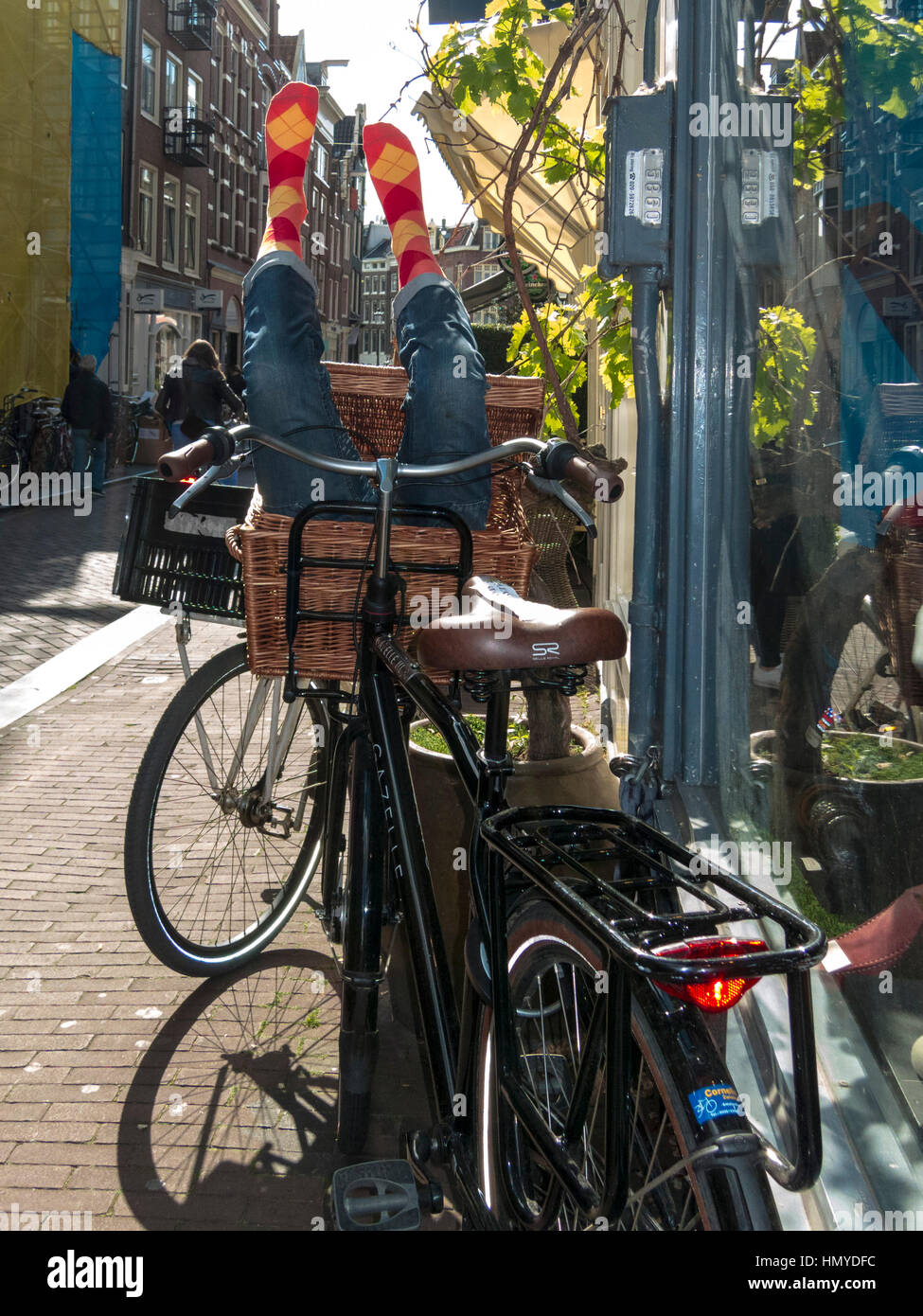 Bicicletta appoggiata contro una finestra con fantoccio gambe sporgenti del cestello Foto Stock