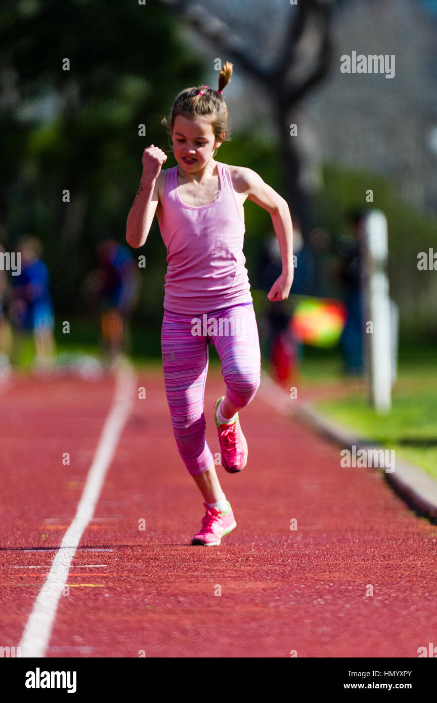 Una bambina corre lungo la pista durante una gara presso una scuola elementare le gare di atletica. Foto Stock