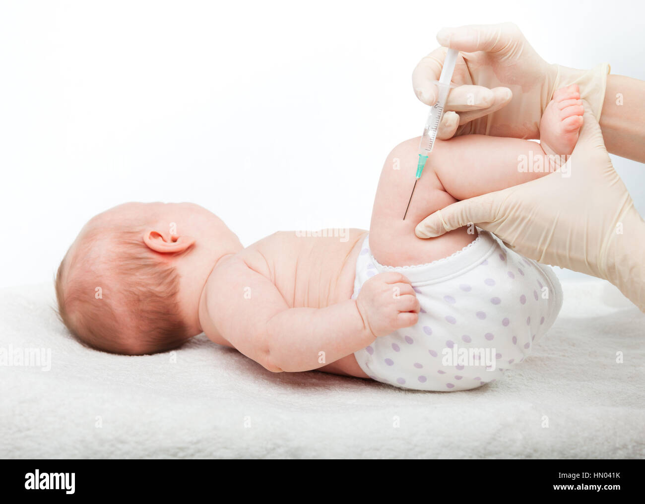 Close-up shot di pediatra dando a tre mesi di baby girl iniezione intramuscolare in gamba su sfondo bianco Foto Stock