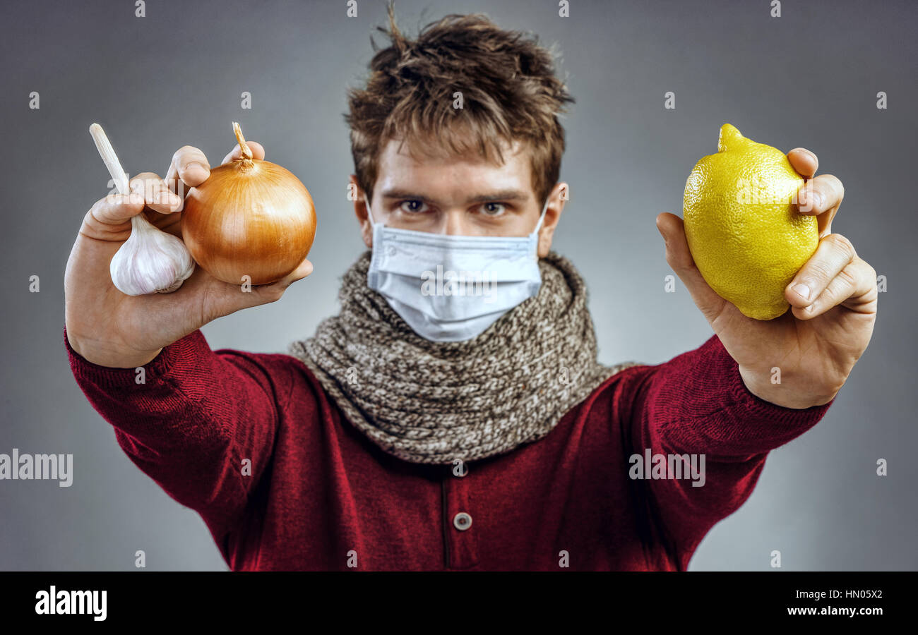 Chill prevenzione. Il giovane uomo sa quali alimenti da una conchiglia: aglio, cipolla, limone. Health care concept Foto Stock