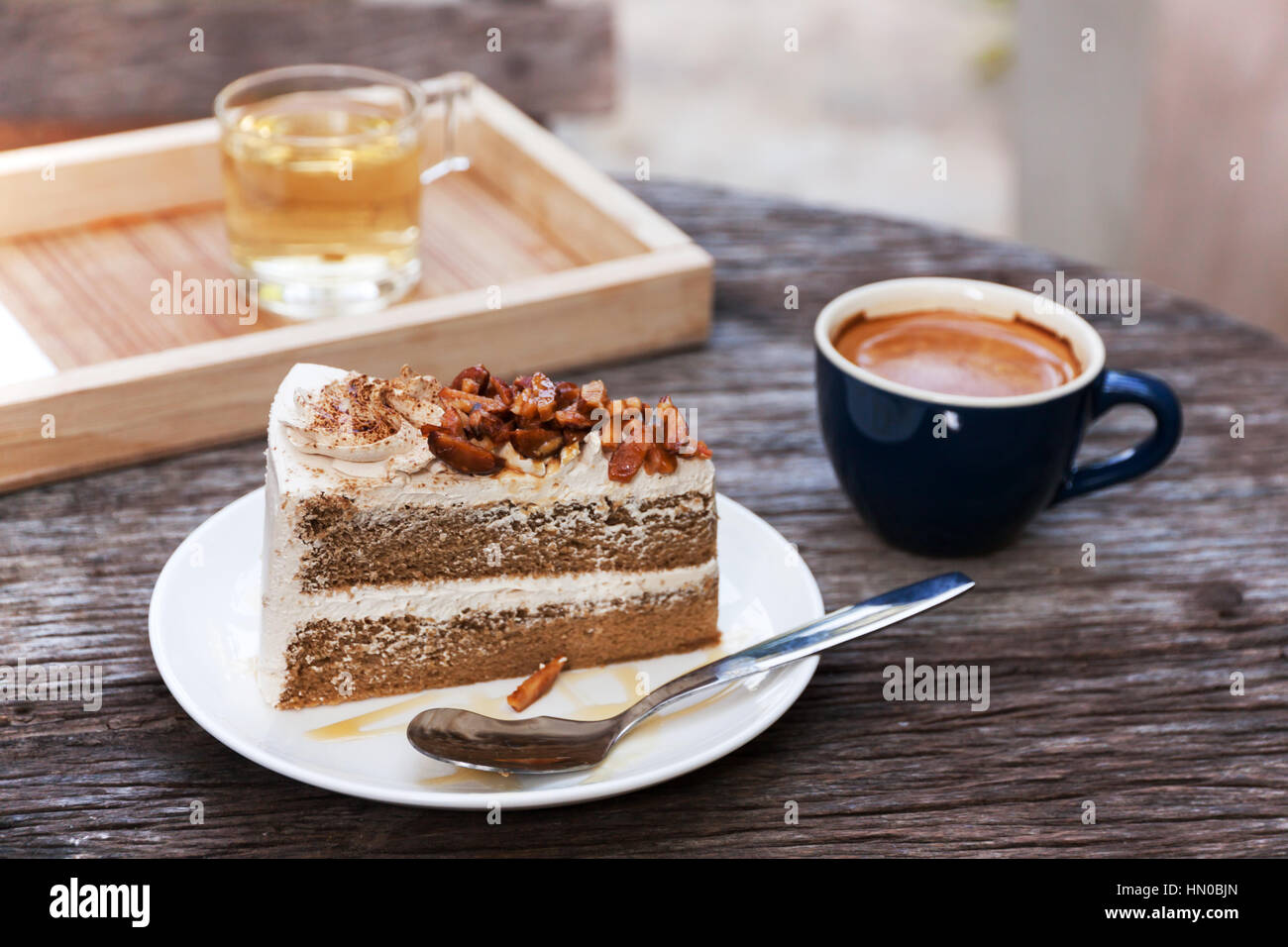 Caffè con torta di mandorle di farcitura sulla piastra bianca e espresso a caldo sul vecchio tavolo in legno Foto Stock