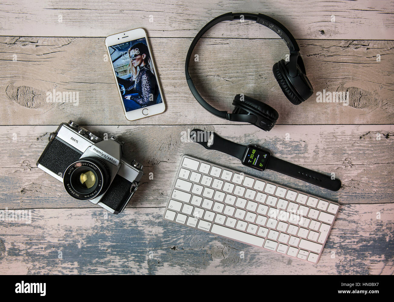 Lay piatto con vecchi film SLR Fotocamera, iPhone, Apple watch, tastiera e cuffie Foto Stock