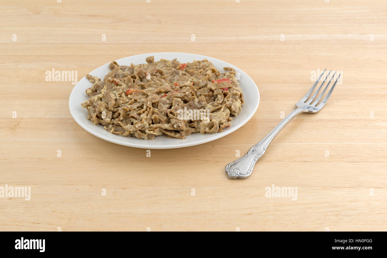 A che serve di edamame fettuccine con una salsa di cocco su una piastra con una forcella per il lato in cima a una tavola di legno alto. Foto Stock