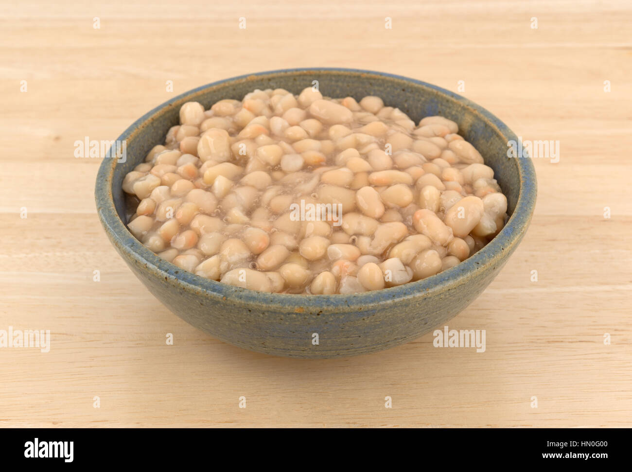 A che serve di organico Fagioli navy in un vecchio recipiente di ceramica in cima a una tavola di legno. Foto Stock
